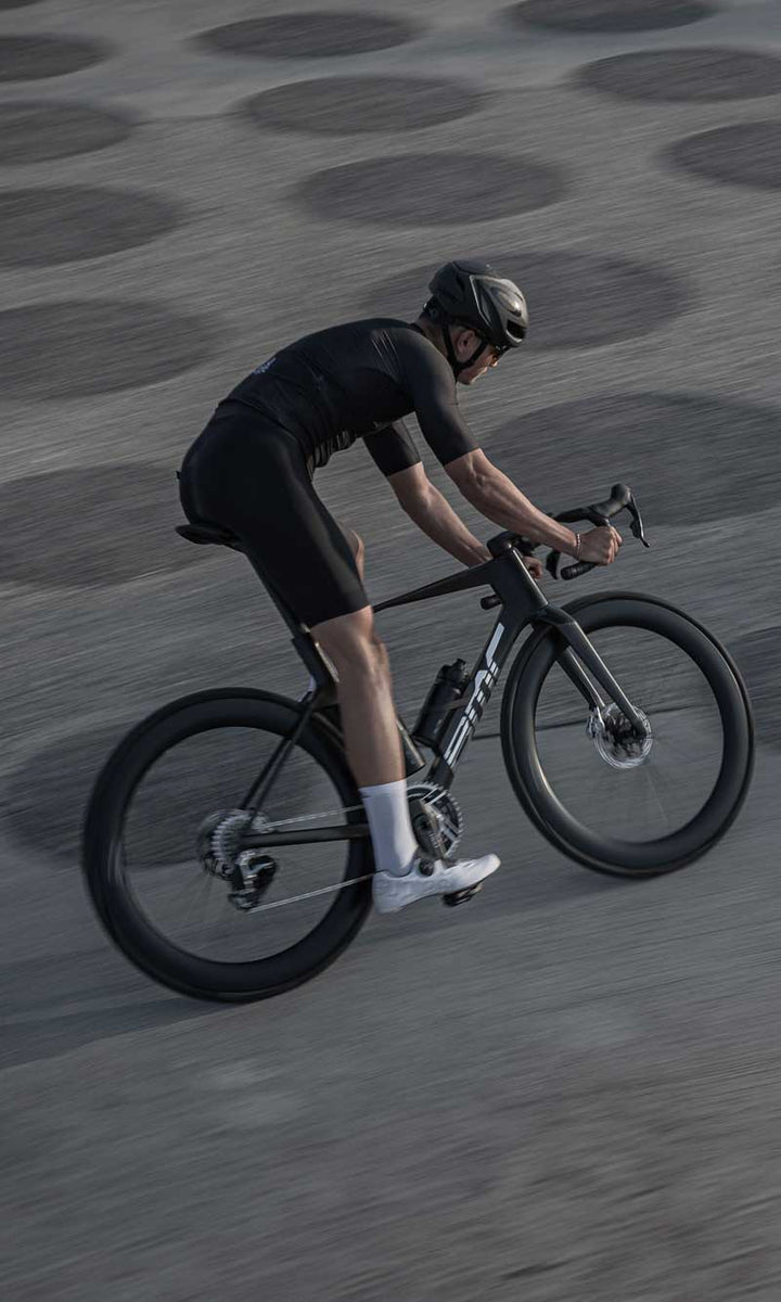 Road biker on the road with black carbon racing bike Teammachine R Mpc from BMC